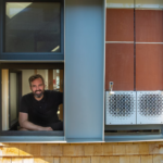 Professor Jonathan Grinham sits inside the window of HouseZero.