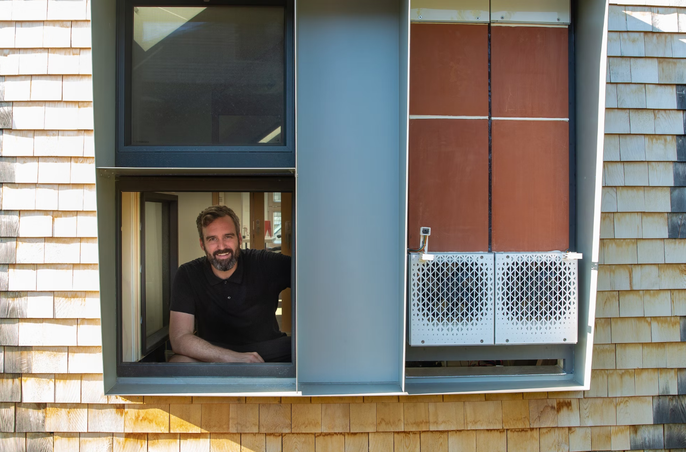 Professor Jonathan Grinham sits inside the window of HouseZero.
